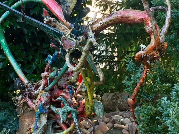 A striking sculpture made entirely of recycled plastic bottles and discarded metal scraps, placed in a park with lush greenery, portraying the message of environmental consciousness.