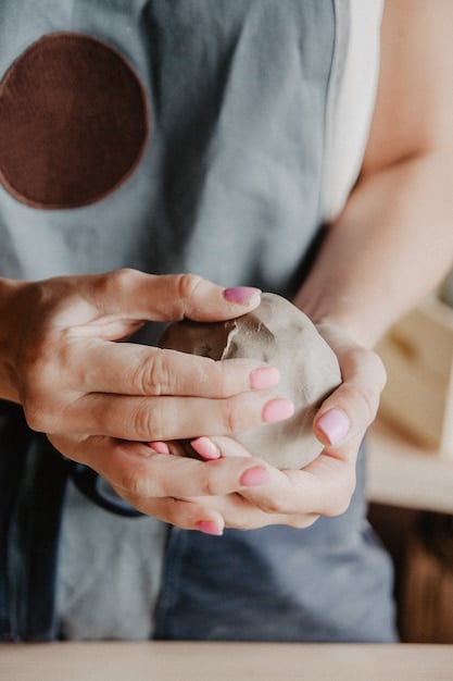 A close-up of a potter's hands shaping clay on a wheel, showcasing the intricate craftsmanship involved in creating local art. The workshop is filled with finished pottery pieces, demonstrating the artist's skill and dedication.