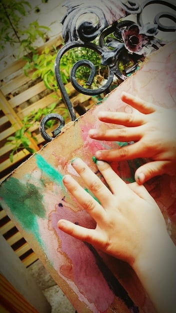 A close-up of hands carefully painting a canvas with a variety of vibrant colors. The hands are holding different brushes, and the focus is on the act of creation and the mixture of colors, symbolizing stress relief and emotional expression.